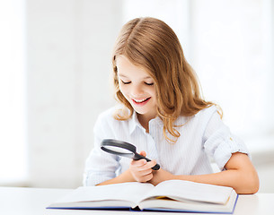 Image showing girl reading book with magnifier at school