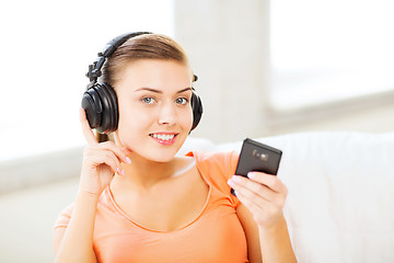 Image showing woman with headphones and smartphone at home