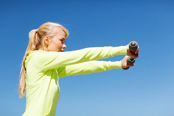 Image showing sporty woman with light dumbbells outdoors