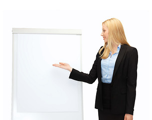 Image showing businesswoman pointing at white blank flipchart