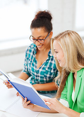 Image showing smiling student girls reading book at school