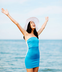 Image showing girl with hands up on the beach