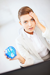 Image showing stressed businesswoman holding clock