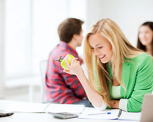 Image showing smiling student girl eating apple at school