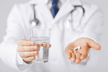 Image showing doctor hands giving white pills and glass of water