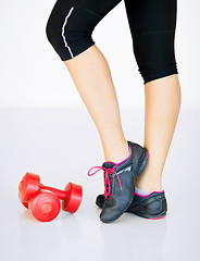 Image showing sporty woman legs with light red dumbbells