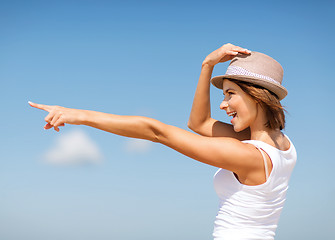 Image showing girl in hat showing direction on the beach