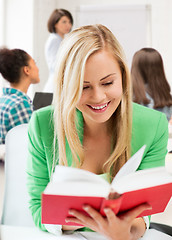 Image showing smiling student girl reading book at school