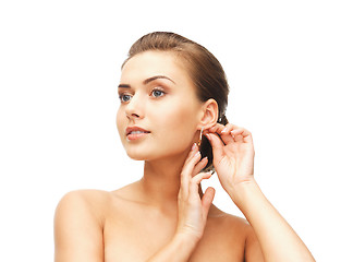 Image showing beautiful woman trying on gold earrings