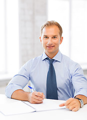 Image showing handsome businessman writing in notebook