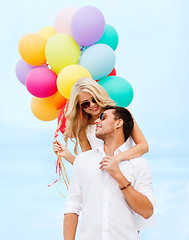 Image showing couple with colorful balloons at seaside