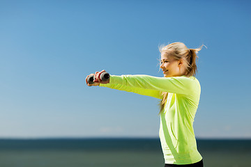 Image showing sporty woman with light dumbbells outdoors