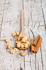 Image showing hazelnuts in wooden spoon and sinnamon sticks