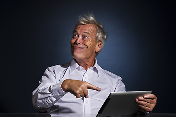 Image showing Senior man grinning and pointing to his tablet