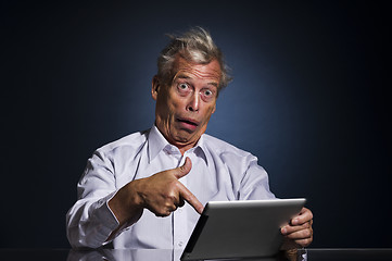 Image showing Shocked senior man pointing to his tablet