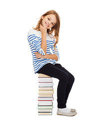 Image showing little student girl sitting on stack of books