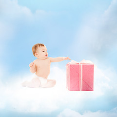 Image showing smiling baby with present on the cloud