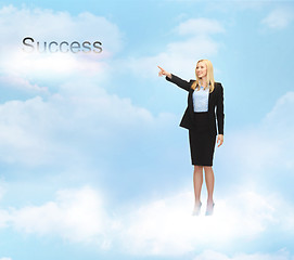 Image showing businesswoman pointing at success word in the sky