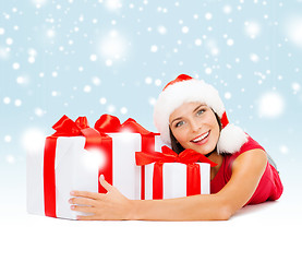 Image showing smiling woman in santa helper hat with gift boxes