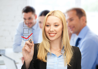 Image showing businesswoman drawing checkmark on virtual screen