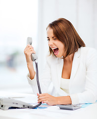 Image showing woman shouting into phone in office