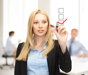 Image showing businesswoman drawing checkmark on virtual screen