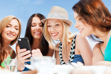 Image showing girls looking at smartphone in cafe on the beach