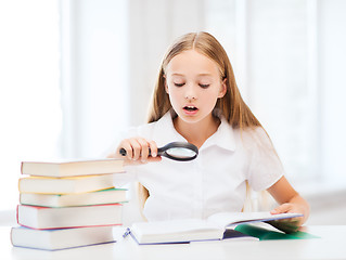 Image showing girl reading book with magnifier at school