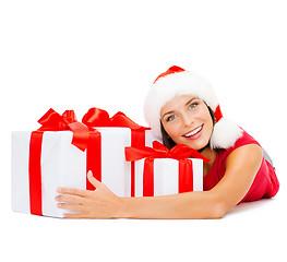 Image showing smiling woman in santa helper hat with gift boxes