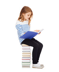 Image showing little student girl sitting on stack of books