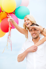 Image showing couple with colorful balloons at seaside