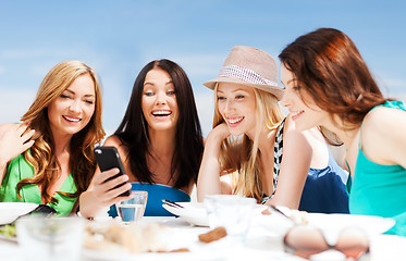 Image showing girls looking at smartphone in cafe on the beach