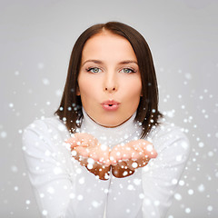 Image showing happy woman in white sweater blowing on palms