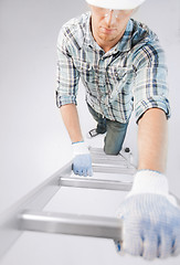 Image showing man in helmet and gloves climbing ladder