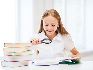 Image showing girl reading book with magnifier at school