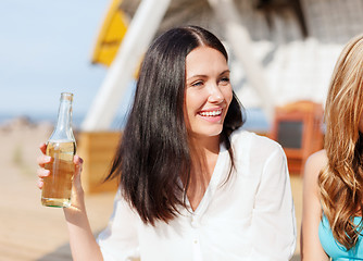 Image showing girl with drink and friends on the beach