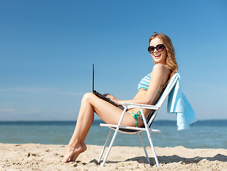 Image showing girl looking at tablet pc on the beach