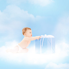 Image showing smiling baby with present on the cloud