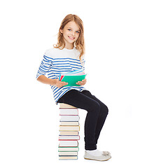 Image showing little student girl sitting on stack of books