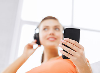 Image showing woman with headphones and smartphone at home