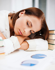 Image showing bored young woman with many books and graphs