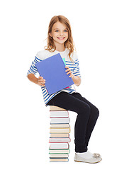 Image showing little student girl sitting on stack of books