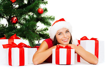 Image showing smiling woman in santa helper hat with gift boxes