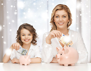 Image showing mother and daughter with piggy banks and money