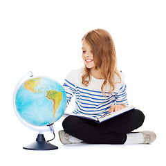 Image showing child looking at globe and holding book