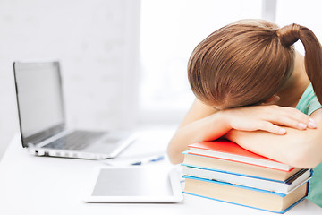 Image showing tired student sleeping on stock of books