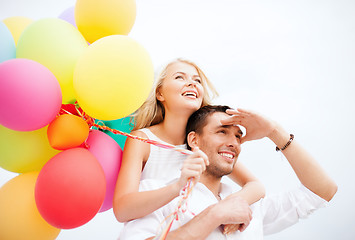 Image showing couple with colorful balloons at seaside