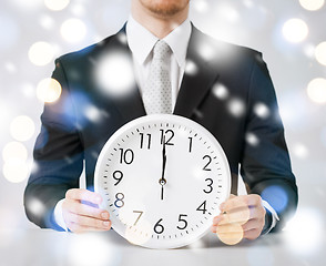 Image showing man holding wall clock showing 12