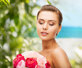 Image showing woman wearing earrings and holding flowers