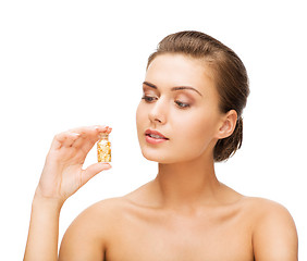 Image showing beautiful woman showing bottle with golden dust